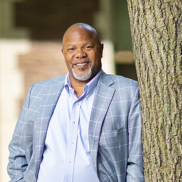 kevin johnson pik professor leaning against a tree